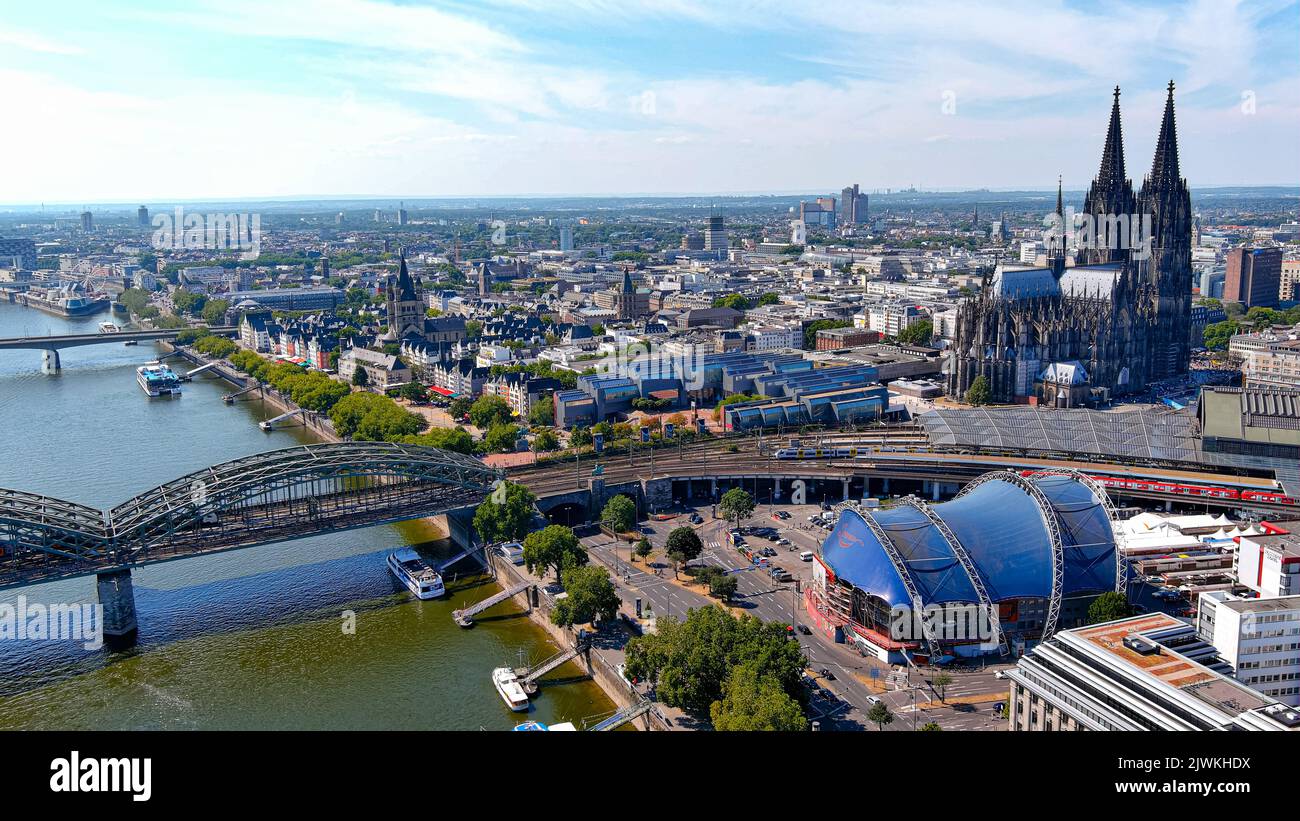 Aerial view of Cologne city on a sunny day. Famous landmark of gothic architecture Cologne Cathedral and Hohenzollern Bridge ft. central train station Stock Photo