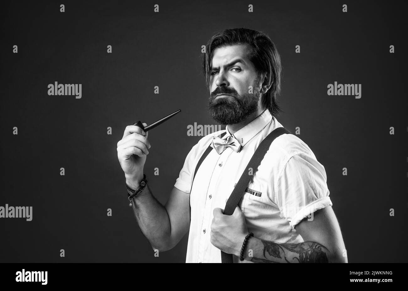 elegant brutal man in formal wear has groomed hair smoking pipe, bad