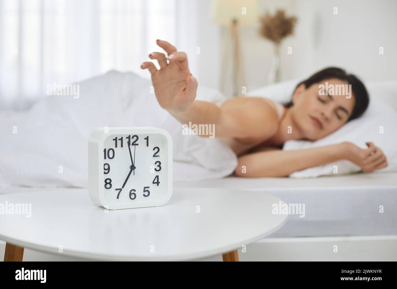 Sleepy woman snooze clock awaken in bed Stock Photo
