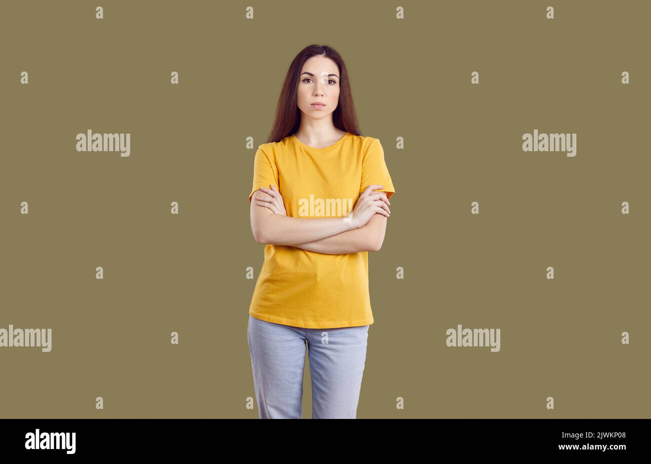 Portrait of angry grumpy young woman who looks at you sternly and skeptically on khaki background. Stock Photo