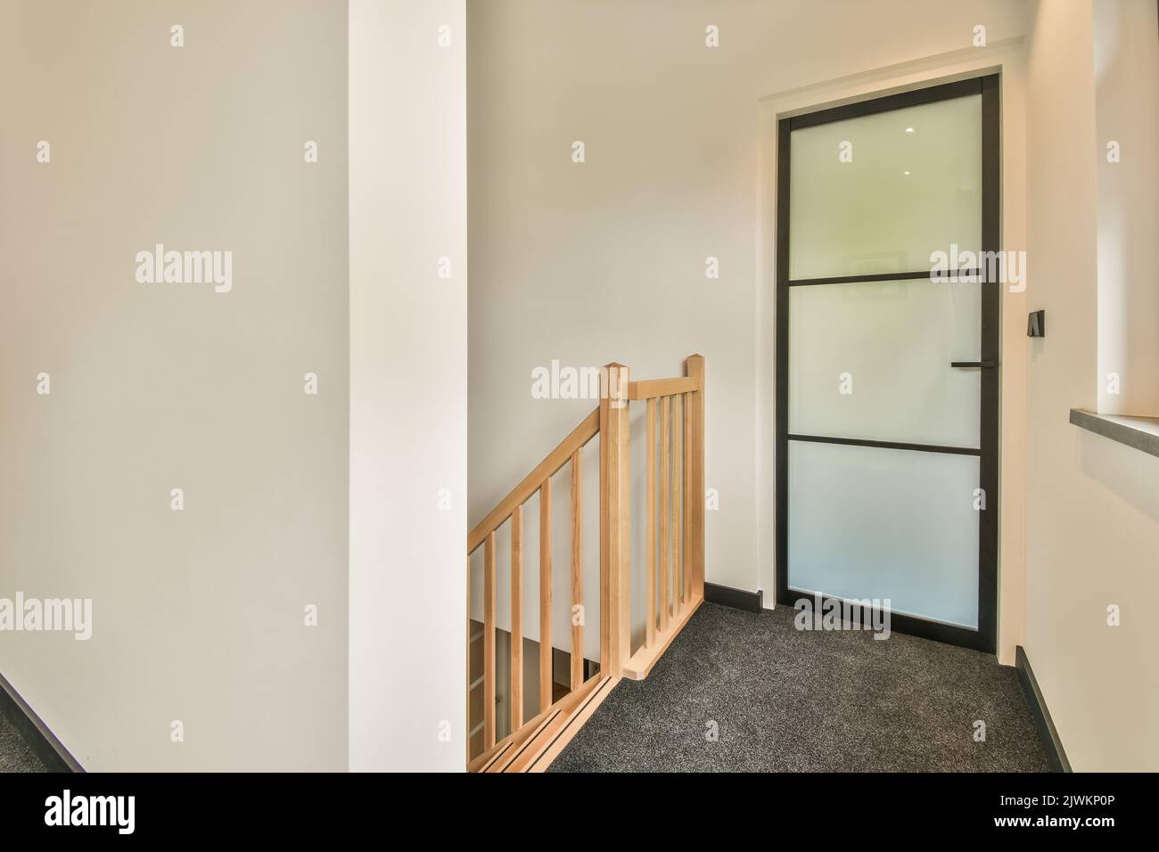 Light narrow hallway with door in two level apartment with minimalist