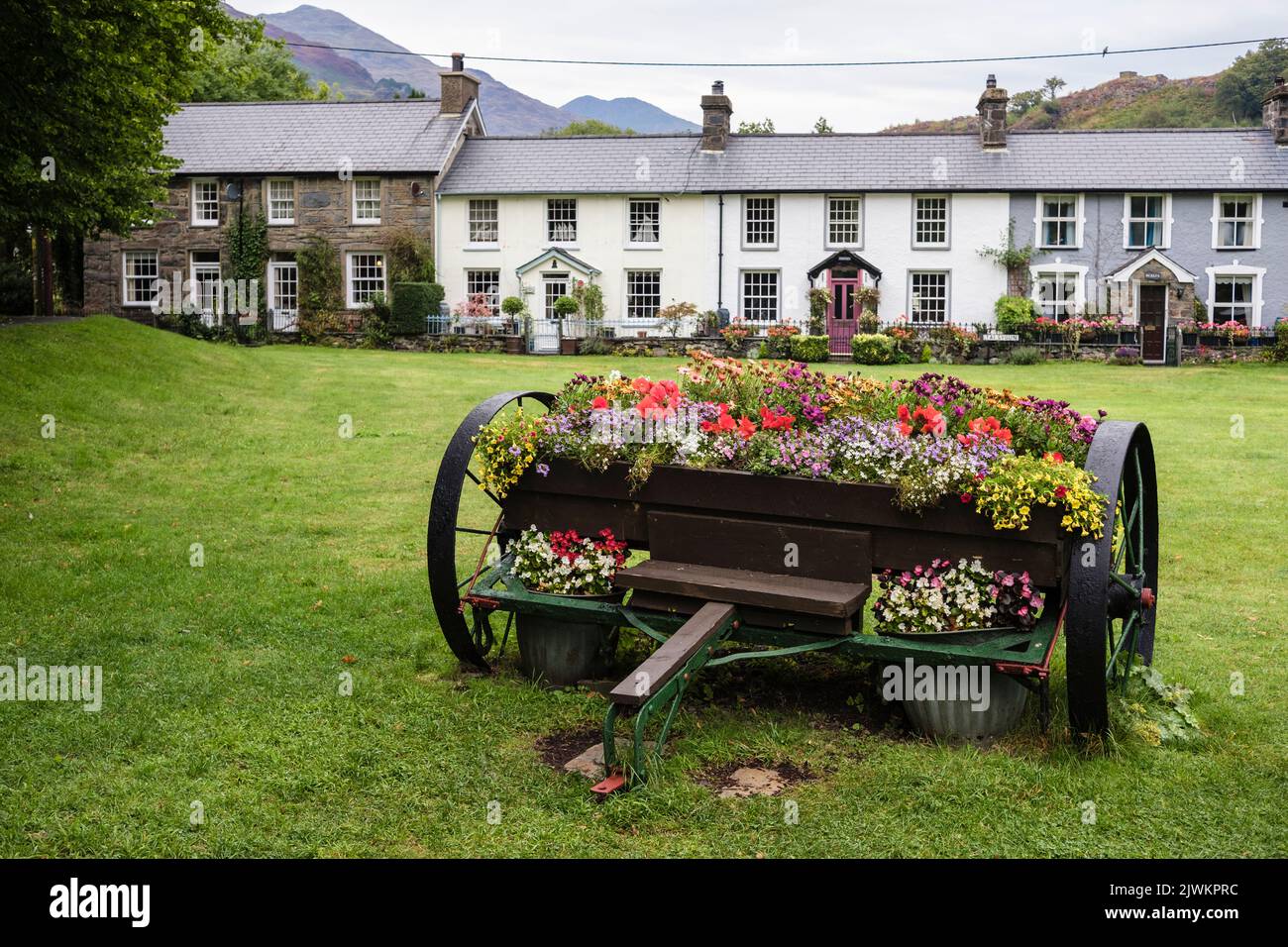 Flower container on village green with traditional old Welsh cottages in summer in Snowdonia National Park. Beddgelert Gwynedd North Wales UK Britain Stock Photo