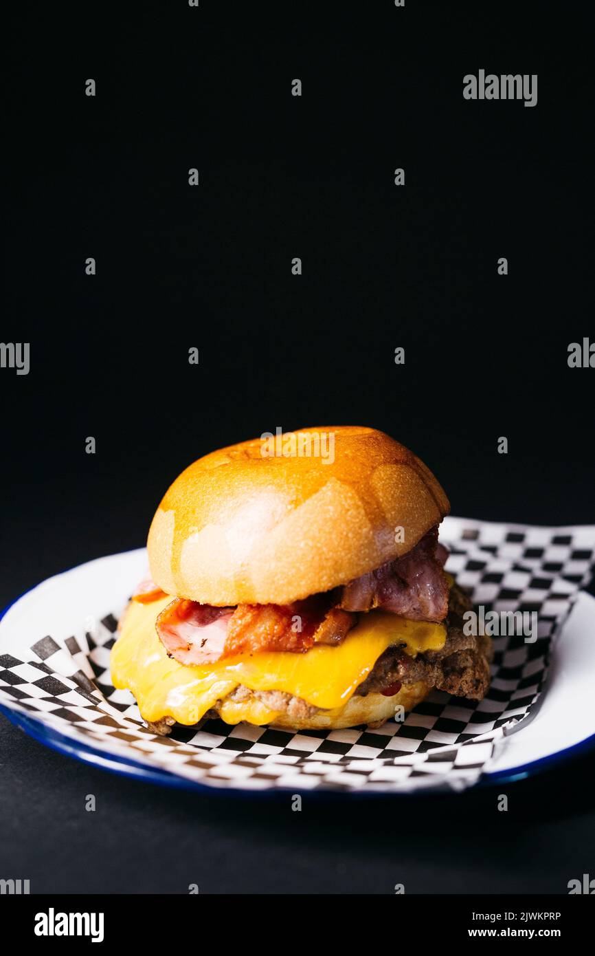 Doble cheeseburger with bacon, melted cheese and ketchup over a black background Stock Photo
