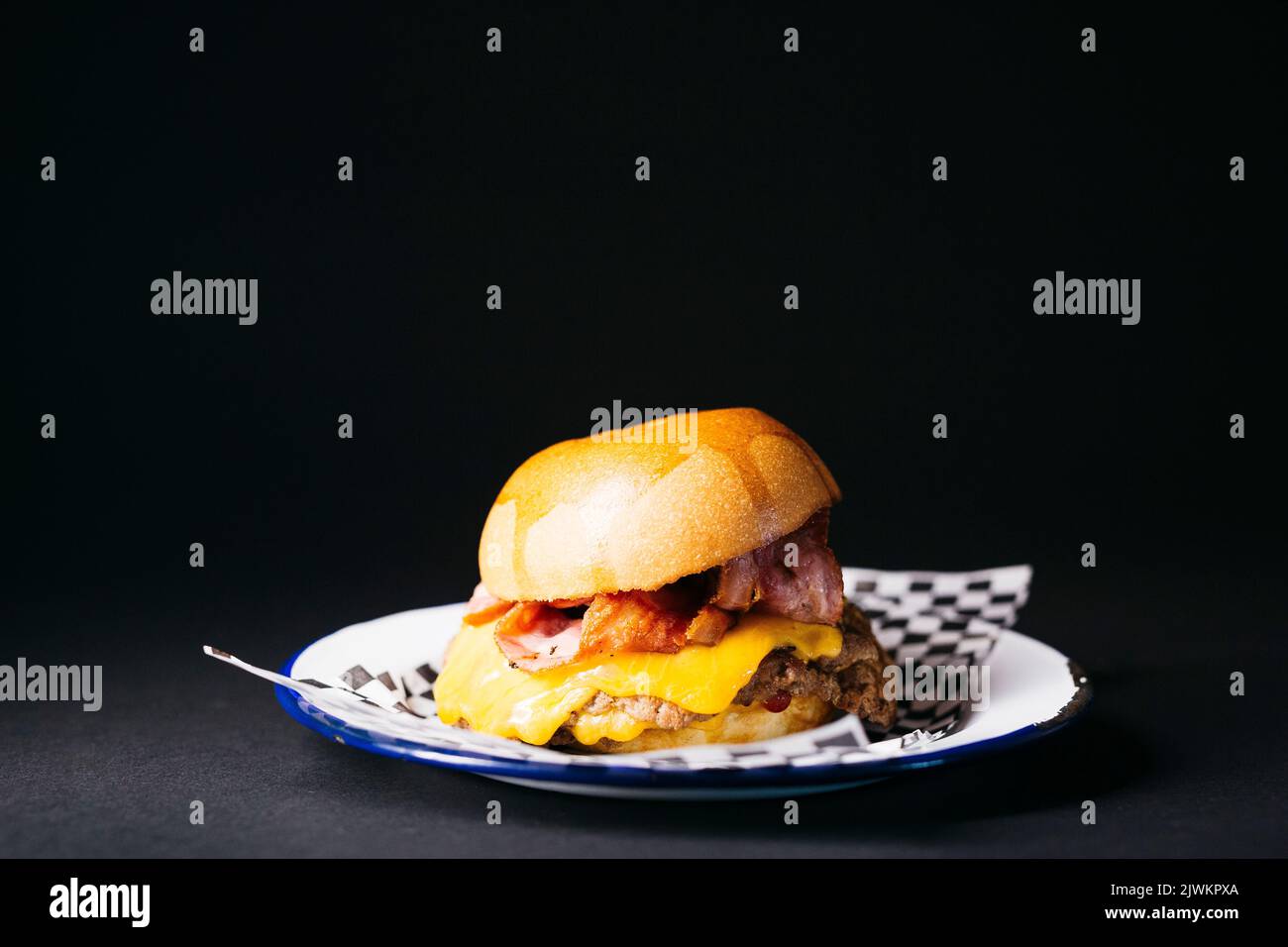 Doble cheeseburger with bacon, melted cheese and ketchup over a black background Stock Photo