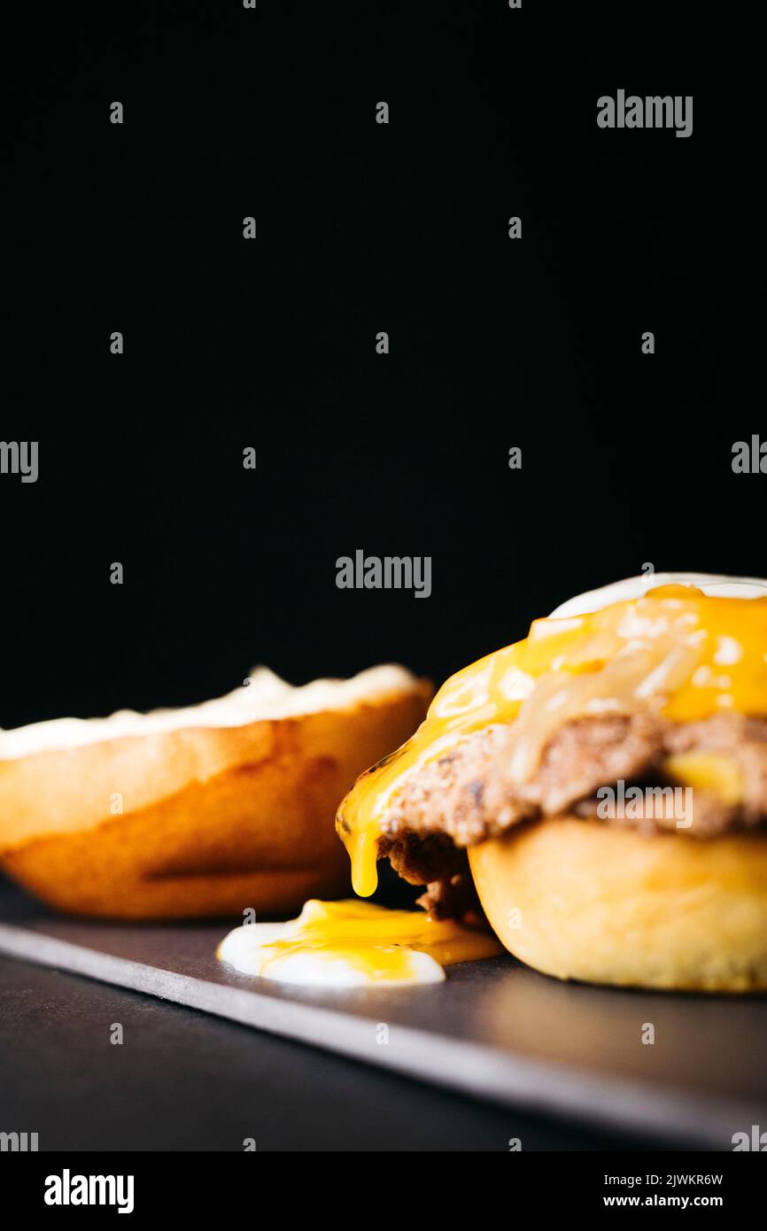 Doble smashburger with coocked onion and a boiled egg over a black background Stock Photo