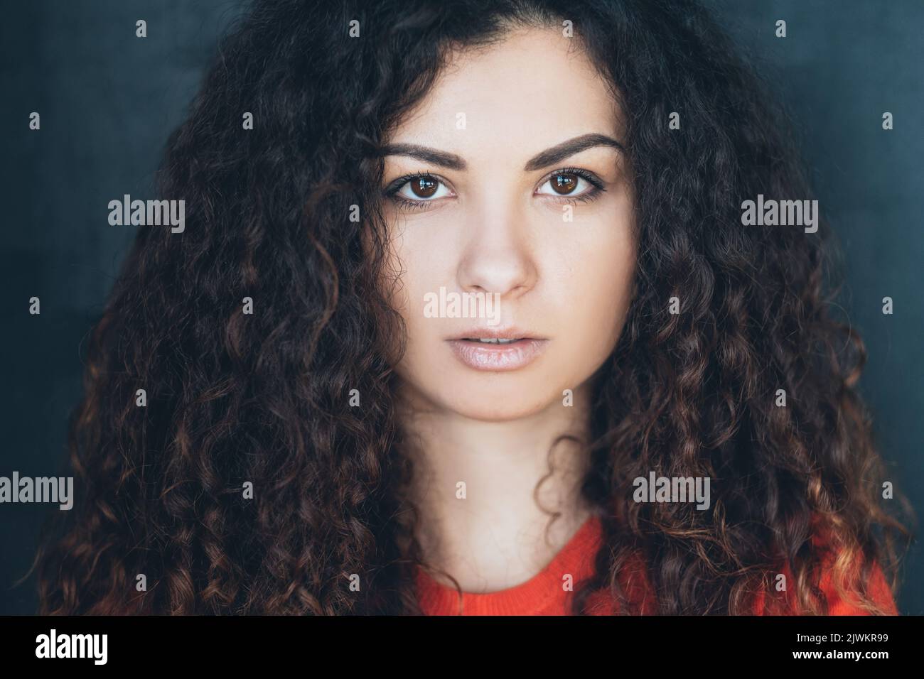 young woman curly hair fixed gaze concentration Stock Photo