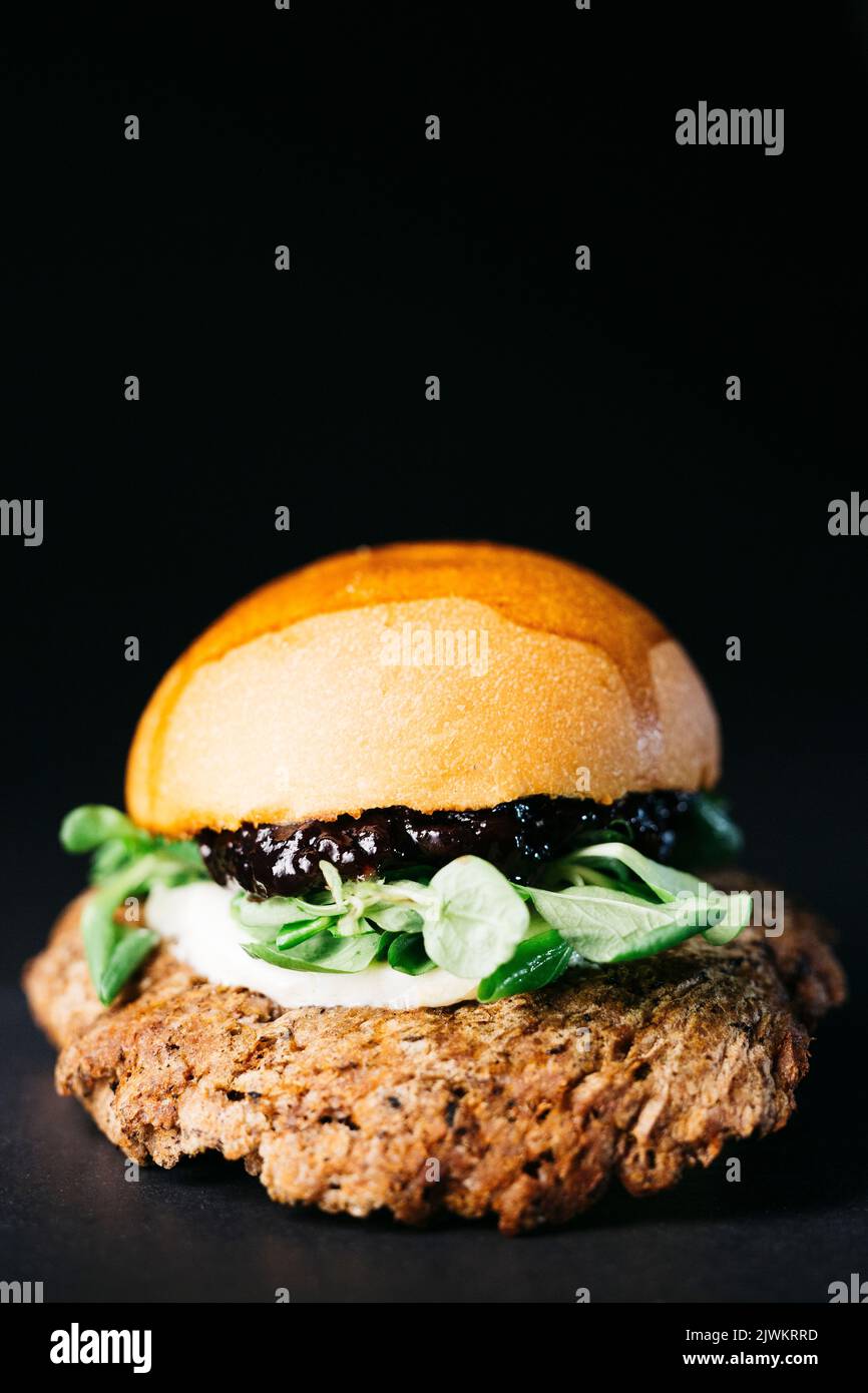 Doble burger with blueberries, vegetables and cheese over a black background Stock Photo