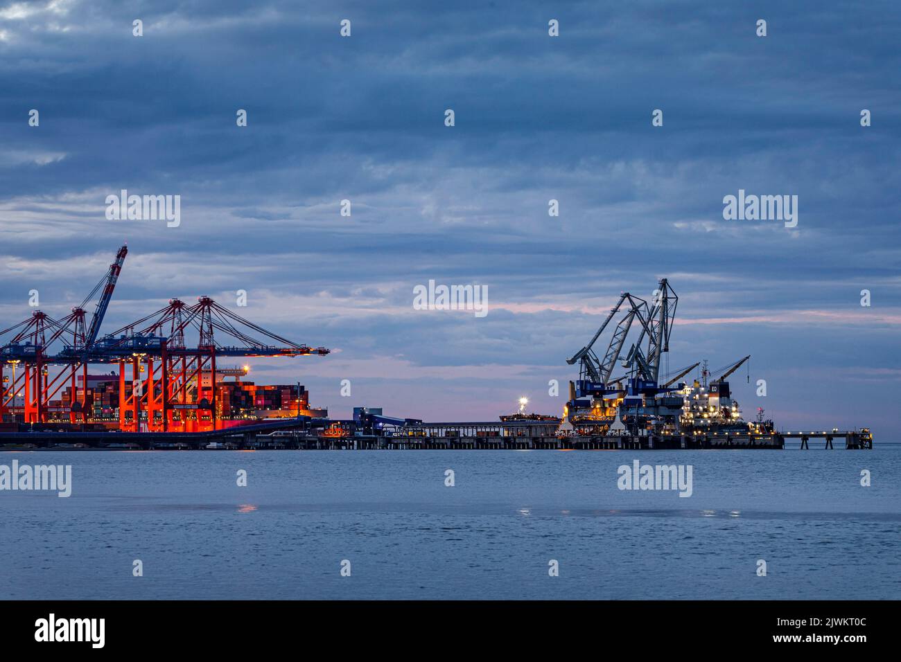 Jade-Weser-Port, container terminal in Wilhelmshafen, cargo handling of a large container ship (left and a general cargo ship (right) Stock Photo
