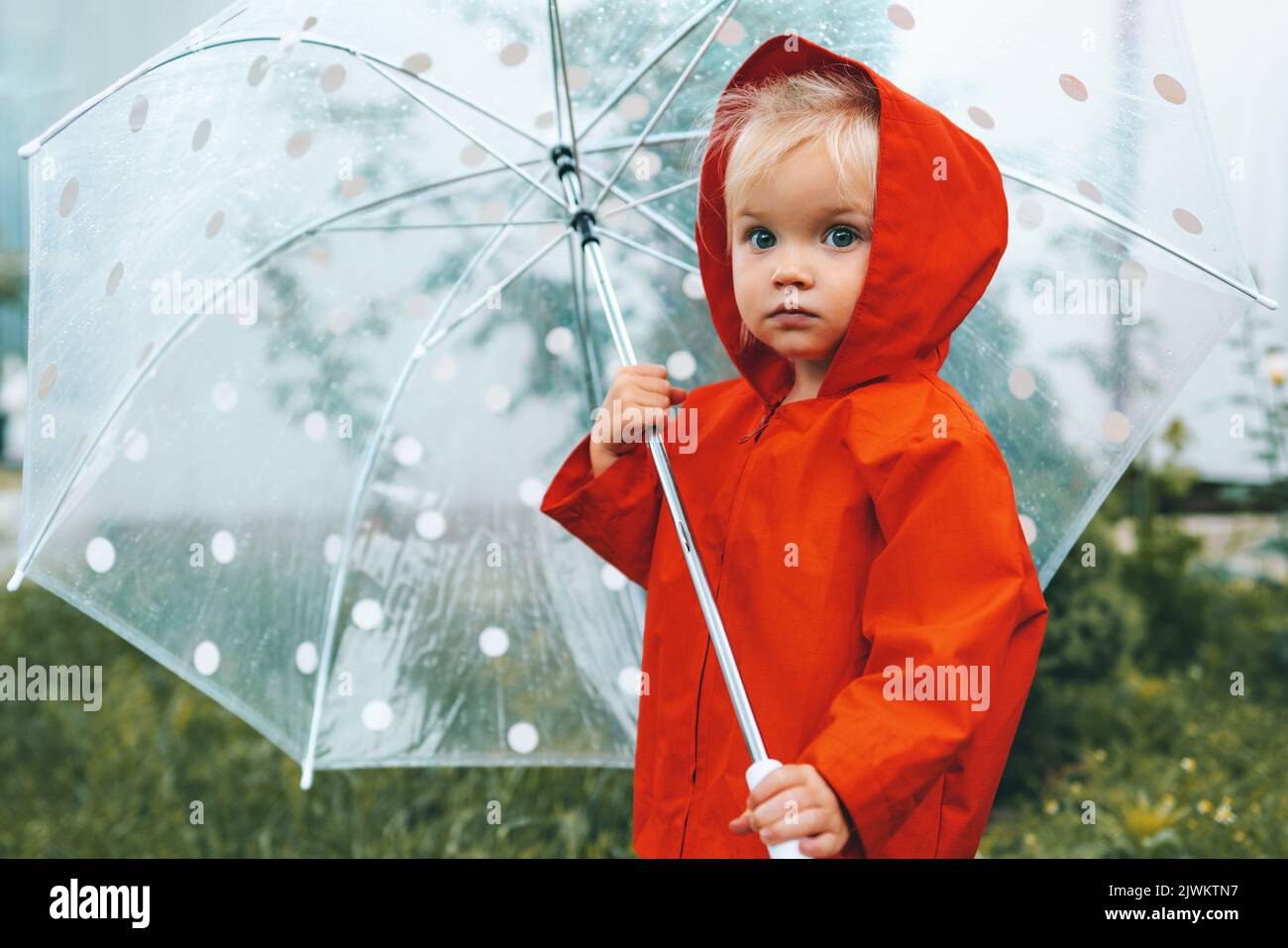 Autumn season child with umbrella walking outdoor wearing red raincoat