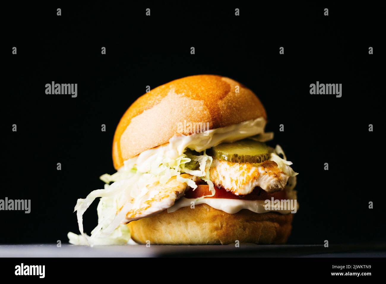 Chicken burger with vegetables over a black background Stock Photo