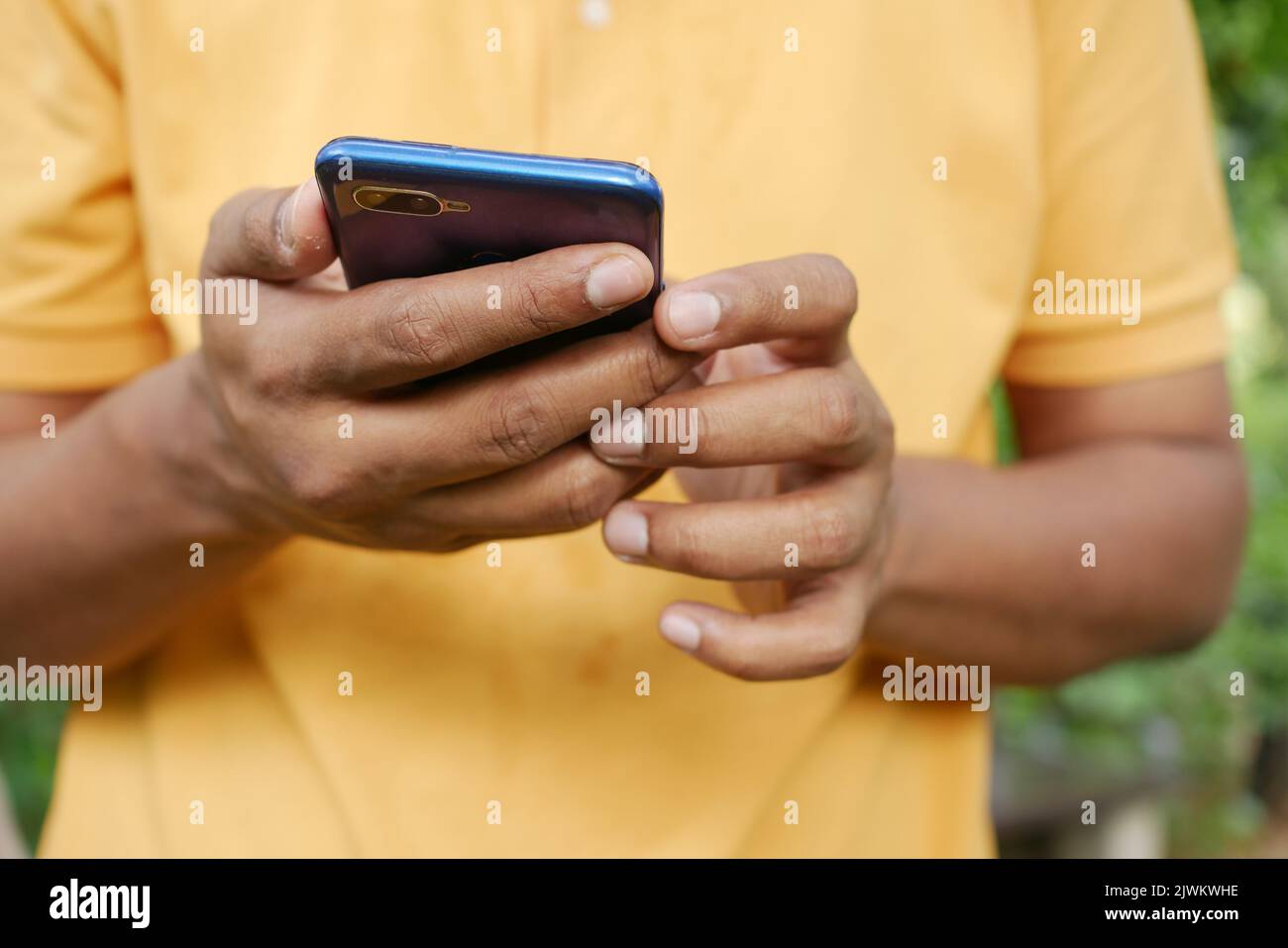 young man in yellow shirt using smart phone. Stock Photo