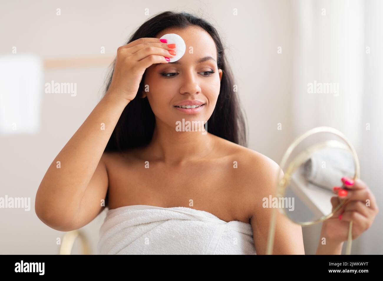 Pretty Woman Using Cotton Pad Cleansing Face Standing In Bathroom Stock Photo