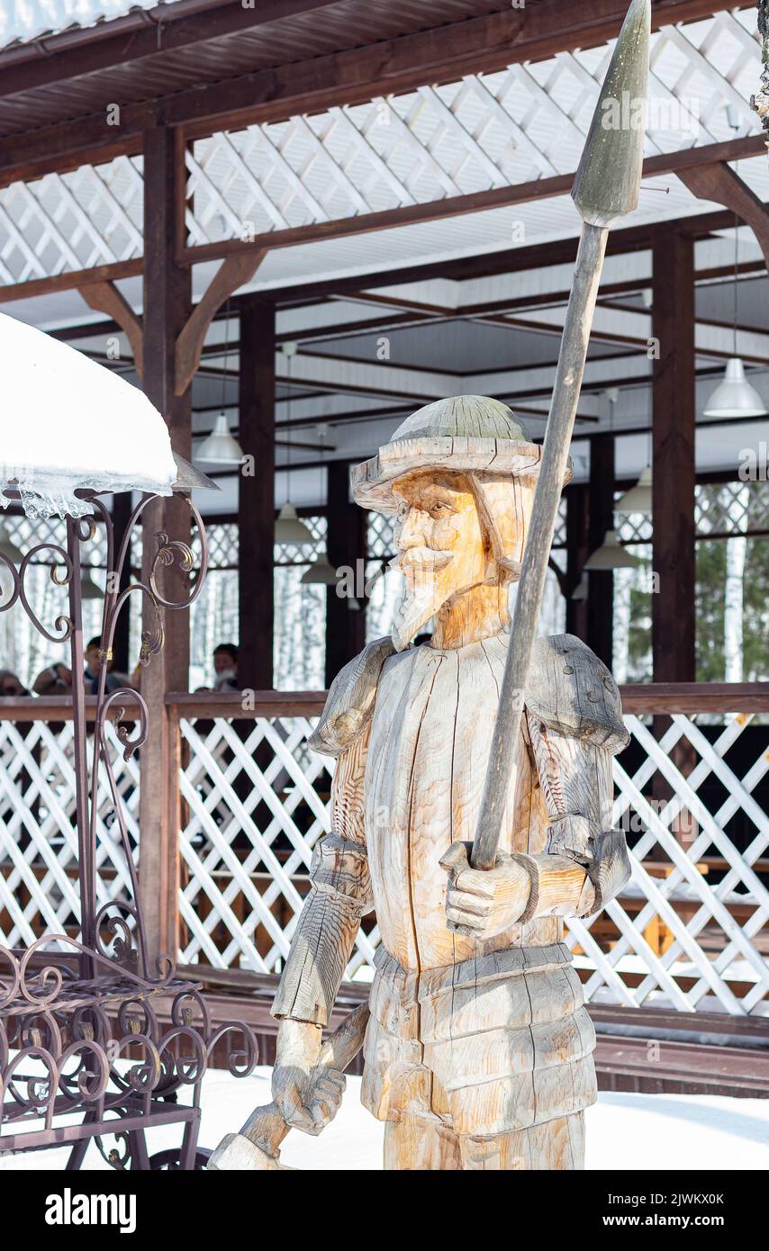 Wooden architecture. Proficiency with cleaver and saw. Creation of sculptures from wood. Wooden sculpture of Don Quixote, knight-errant. Siberian wood Stock Photo