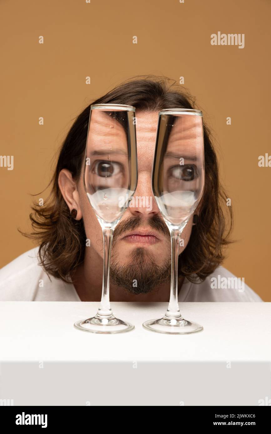 Happy man's face through wine glasses. Object distortion, optical