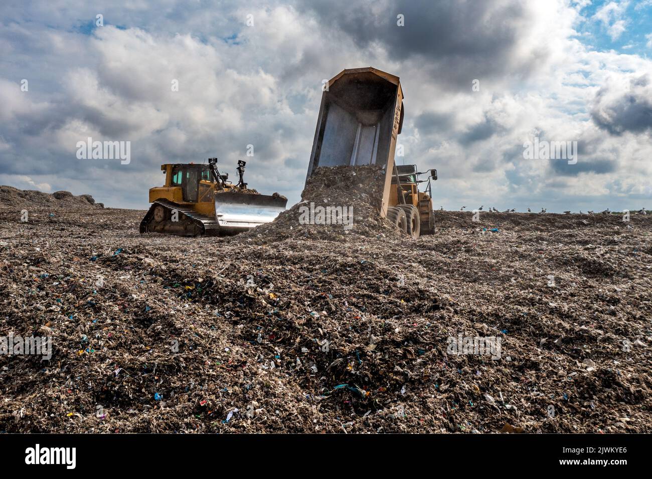 A dumper truck on a large waste management landfill site dumping rubbish in an environmental issue image Stock Photo