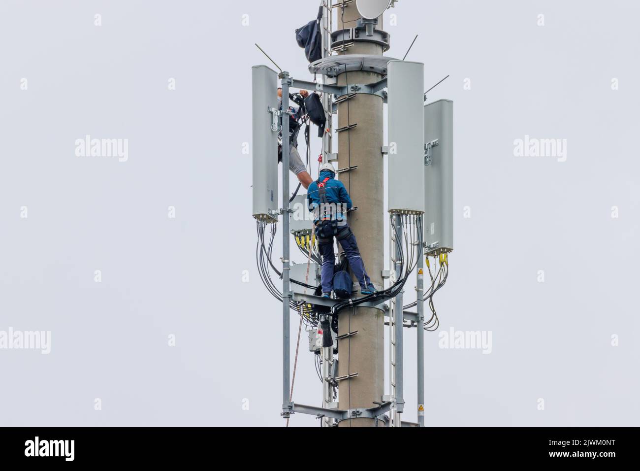 two Telekom technicians perform work on a transmission tower Stock Photo