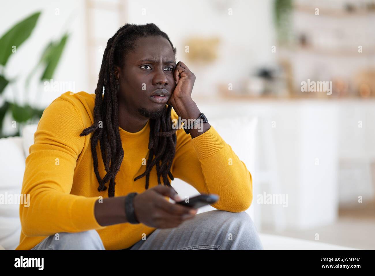 Boring Program. Portrait Of Bored Young Black Guy Watching TV At Home Stock Photo
