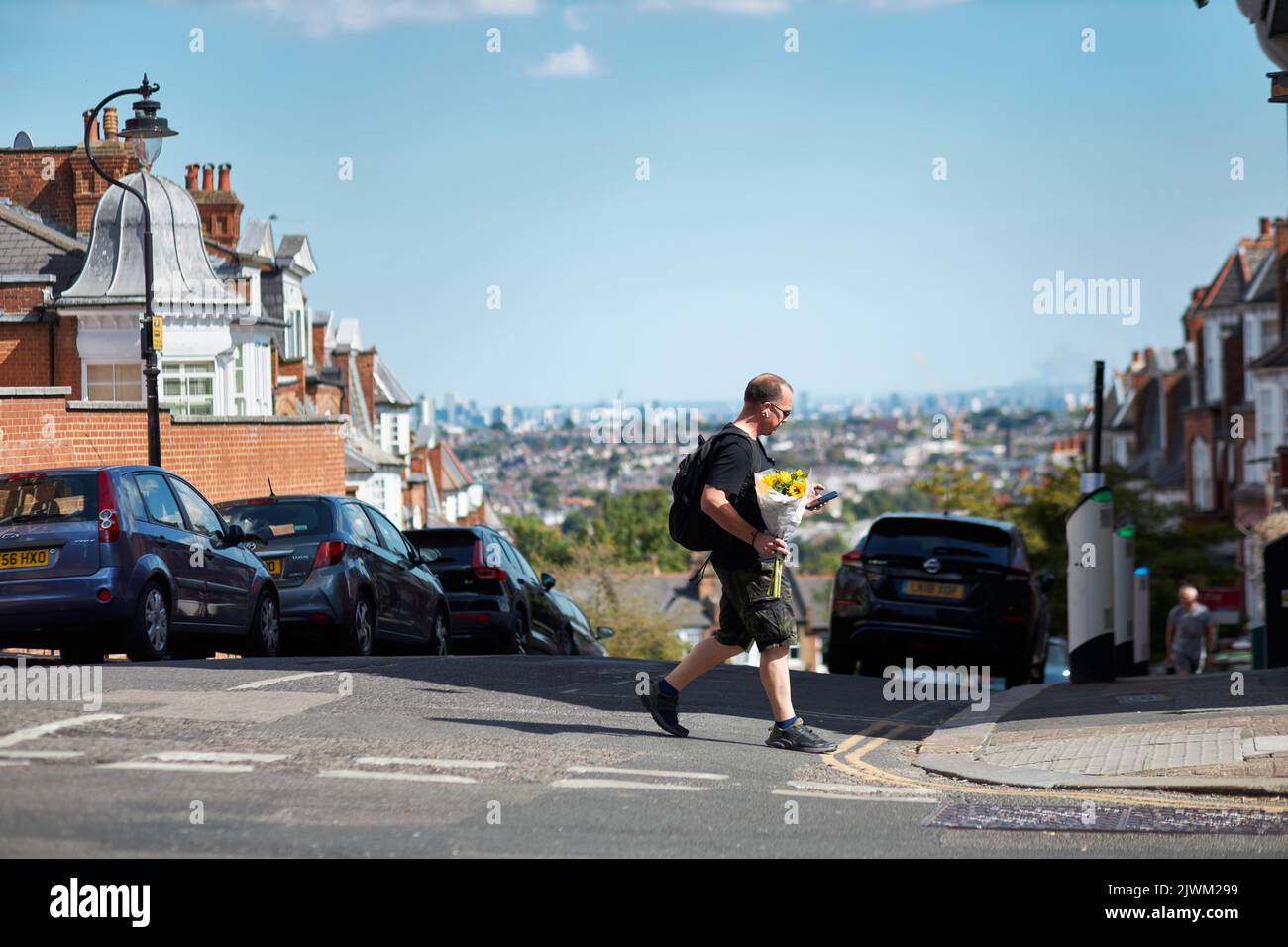 A man holding bunch of flowers walking in Muswell Hill with the London skyline in the background. Stock Photo