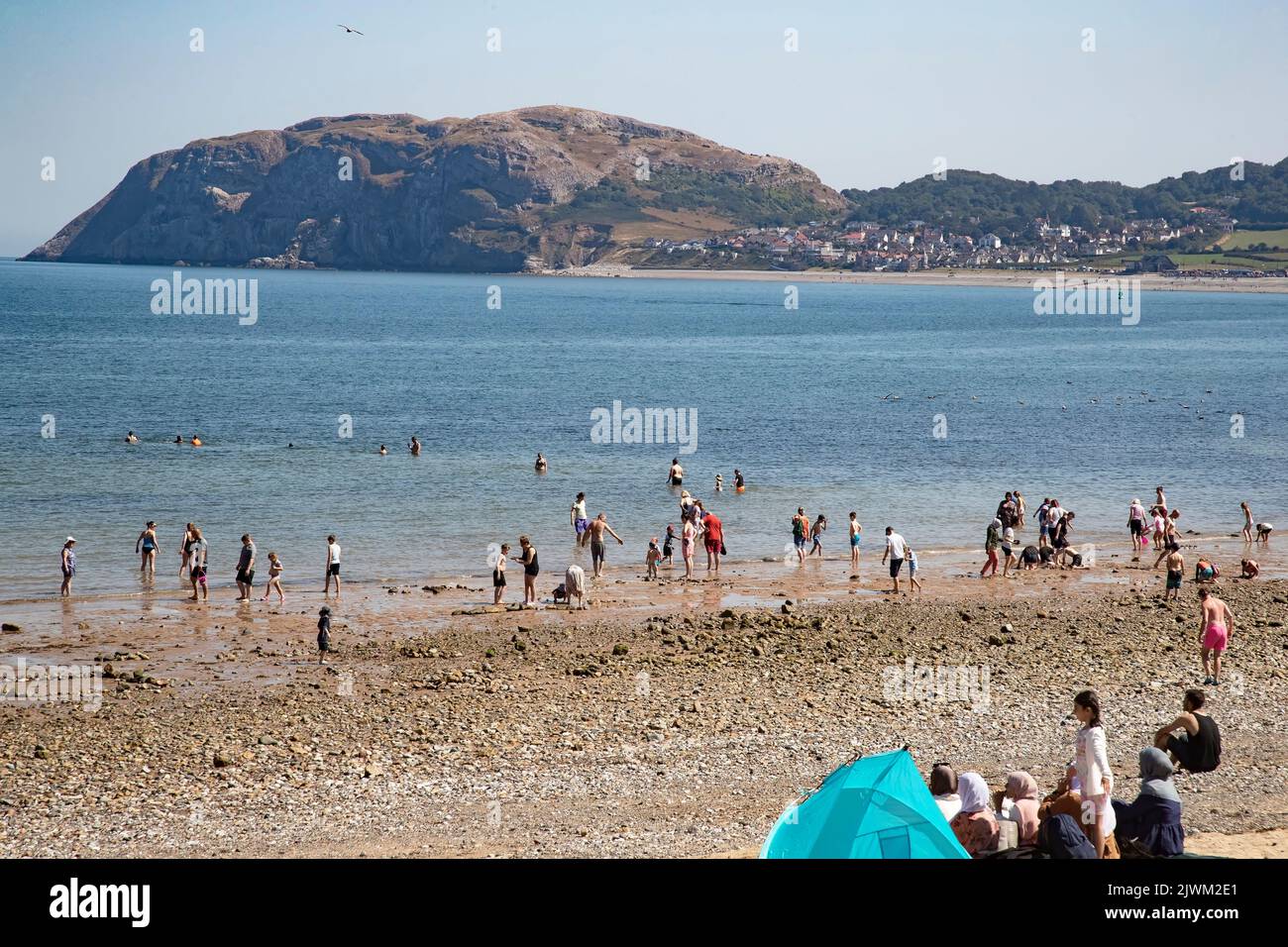 Bathers and beachgoers on the North Shore at Llandudno, Conwy  enjoying the hot summer sun and sea with the Little Orme headland in the background Stock Photo