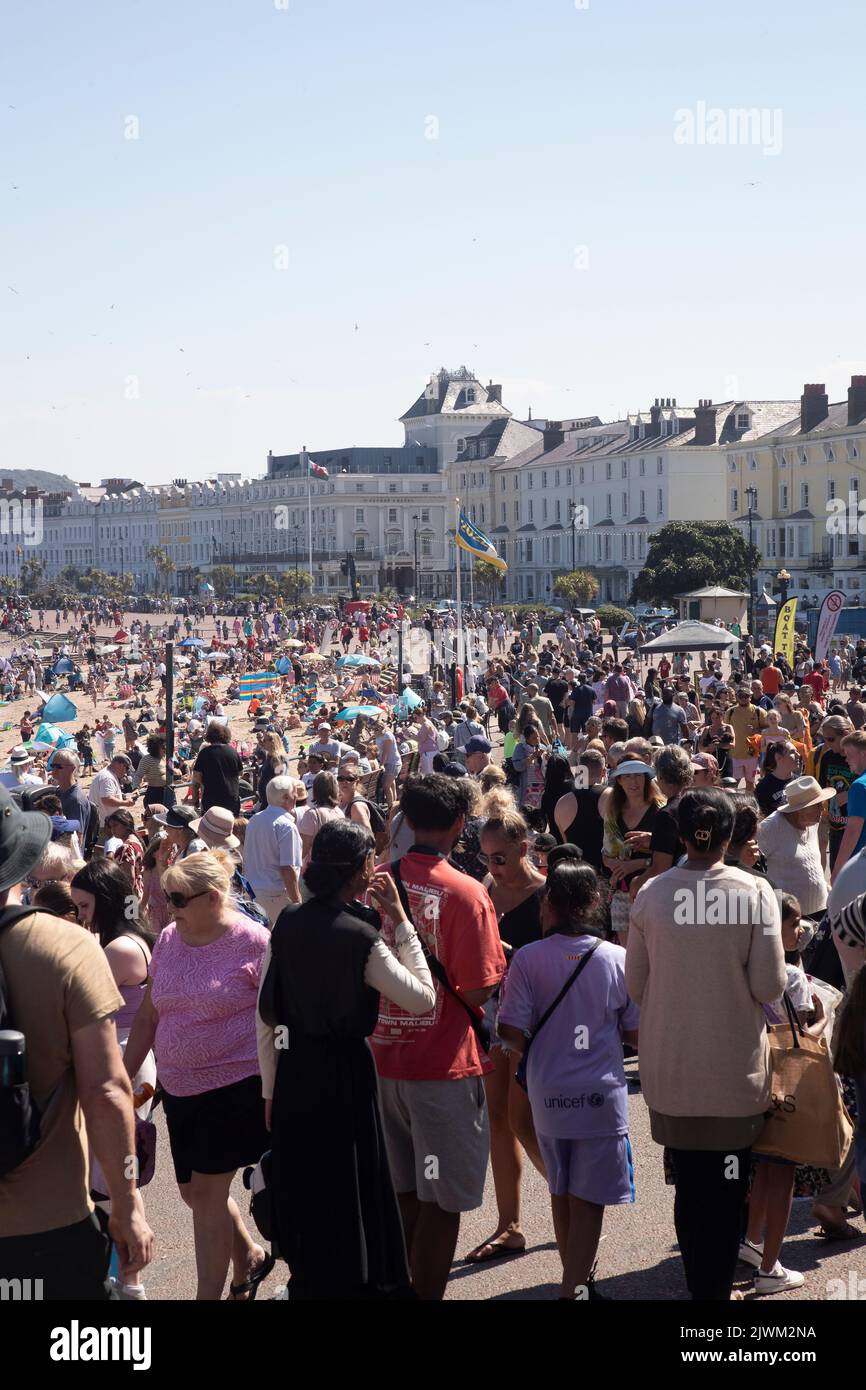 Crowds of holidaymakers and tourists line the North Shore Promenade and beach in Llandudno, North Wales in Summer Stock Photo