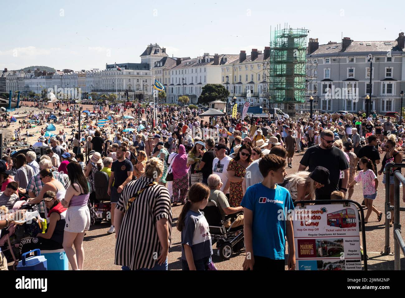 Crowds of holidaymakers and tourists line the North Shore Promenade and beach in Llandudno, North Wales in Summer Stock Photo