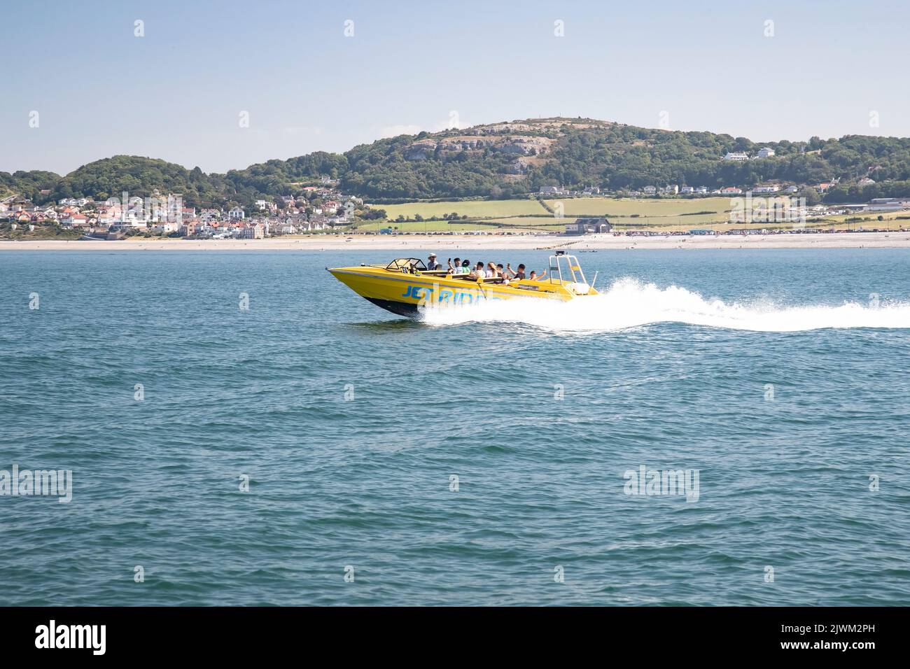 Tourists at Llandudno's North Shore enjoying a seaside power boat trip around the bay in mid Summer between the Great Orme and Little Orme headlands Stock Photo