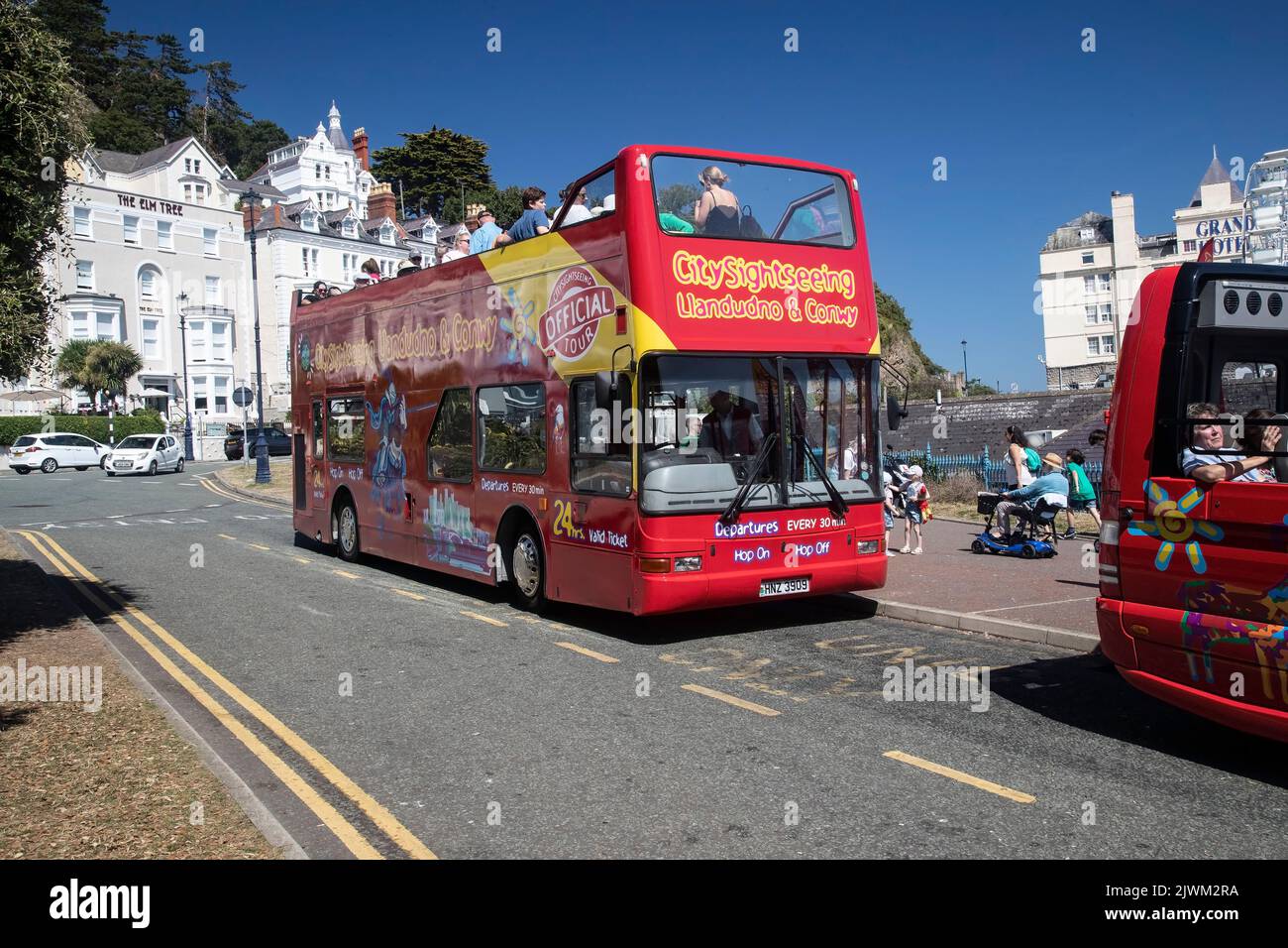 Llandudno sightseeing buses adjacent to the pier offering hop on-hop off bus tours of the town and surrounds for visitors and tourists Stock Photo