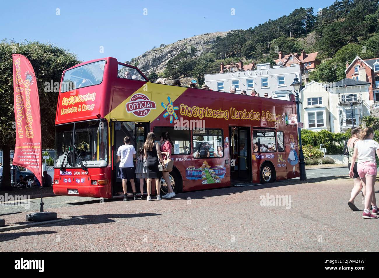 Llandudno sightseeing bus adjacent to the pier offering hop on-hop off bus tours of the town and surrounds for visitors and tourists Stock Photo