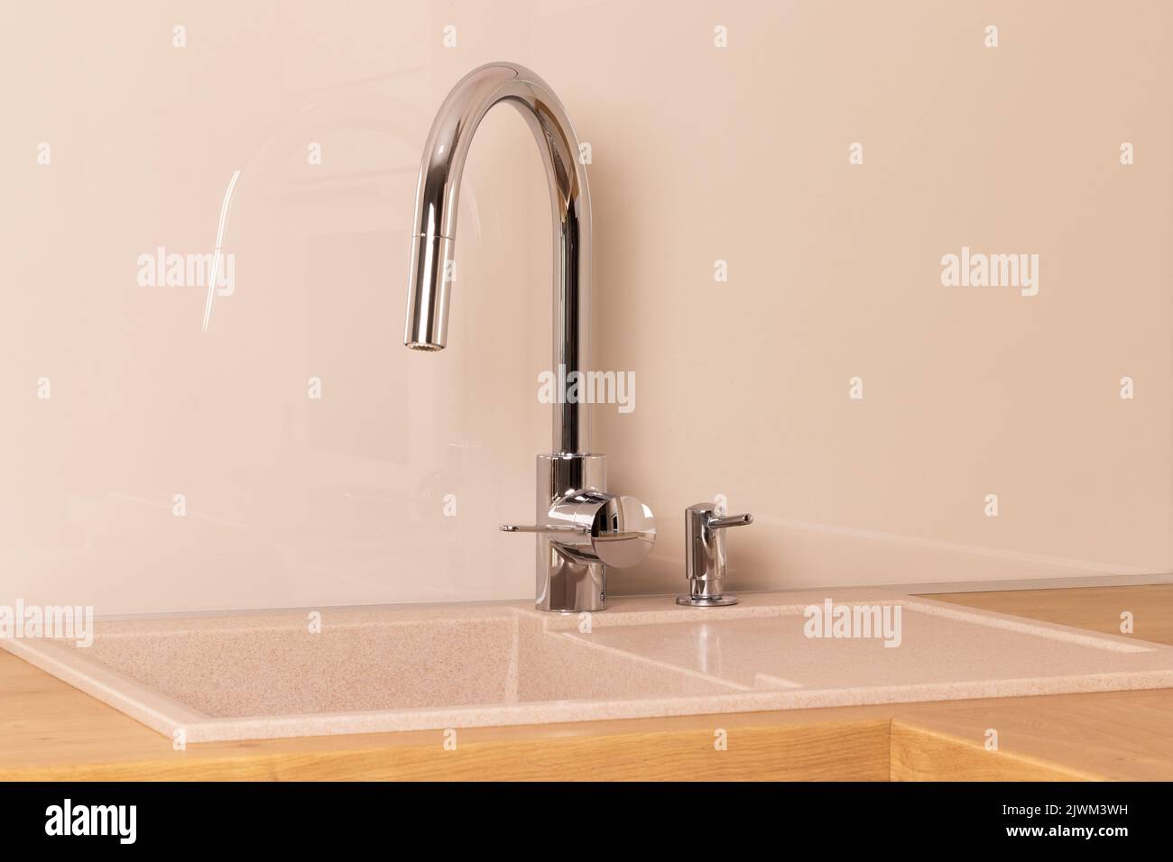 Chrome faucet and builtin dishwashing liquid soap dispenser in modern