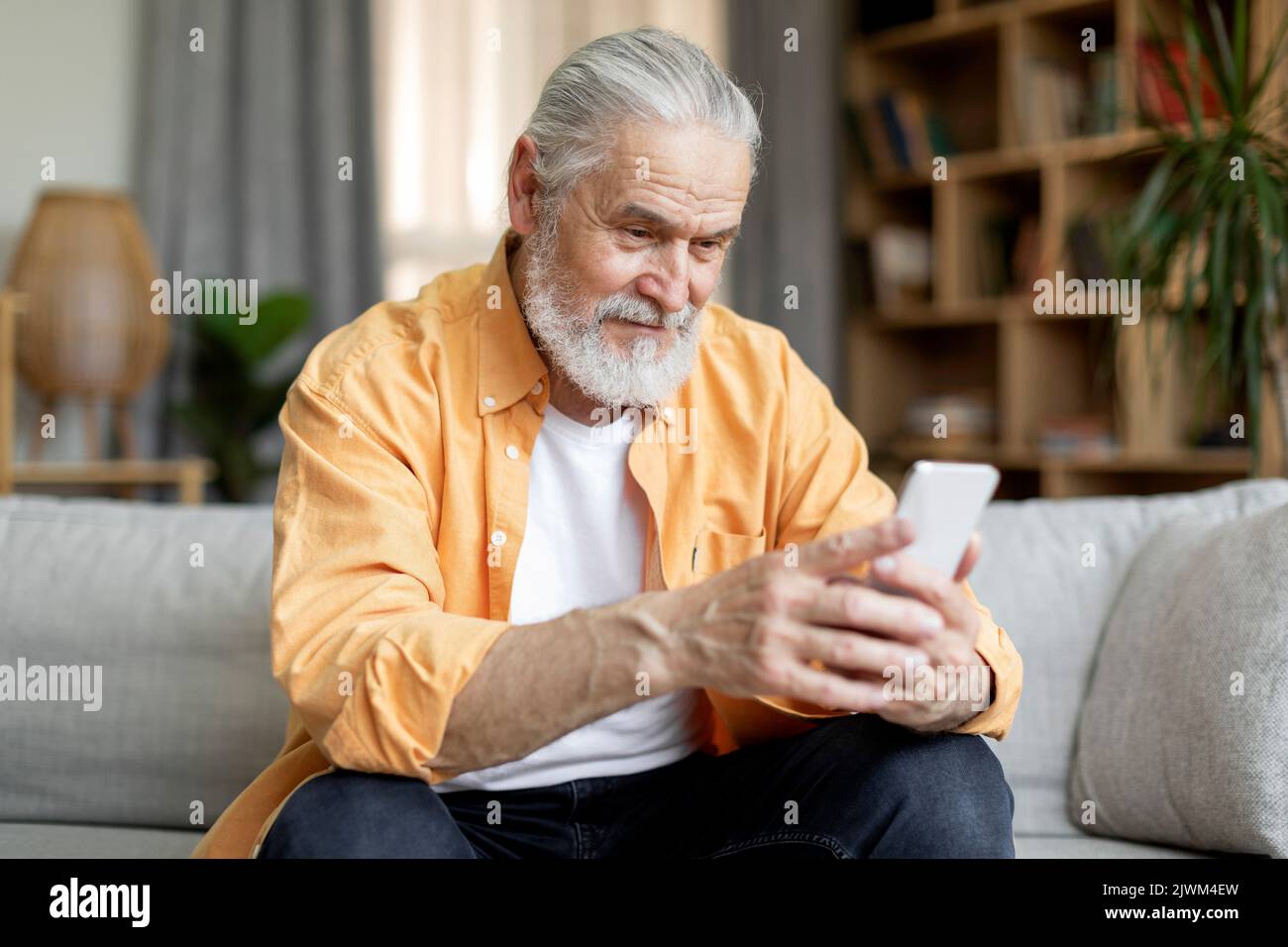Happy senior man using smartphone at home Stock Photo