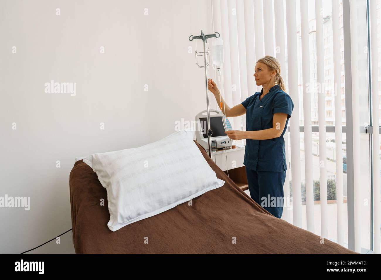 Professional nurse preparing an intravenous drip before procedure in hospital ward Stock Photo