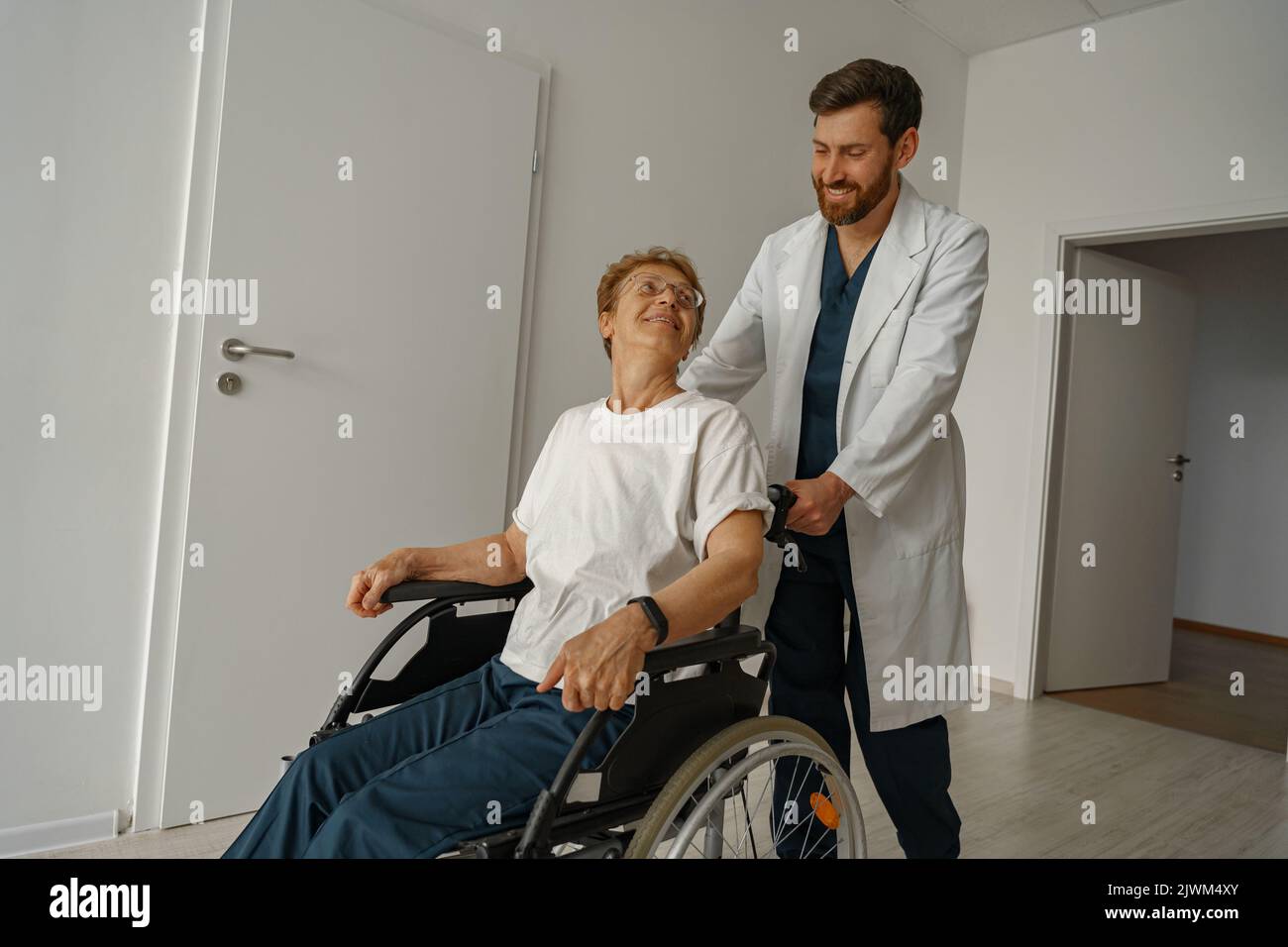 Professional male doctor carrying female patient on wheelchair in