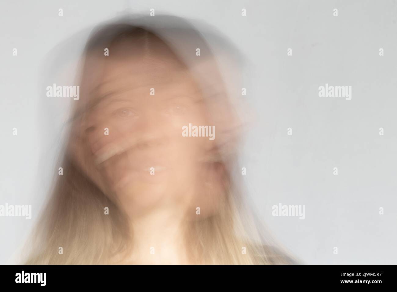 Long exposure photo with a screaming and hysterical head of a girl on an isolated background, screaming and siteria, bad mood Stock Photo