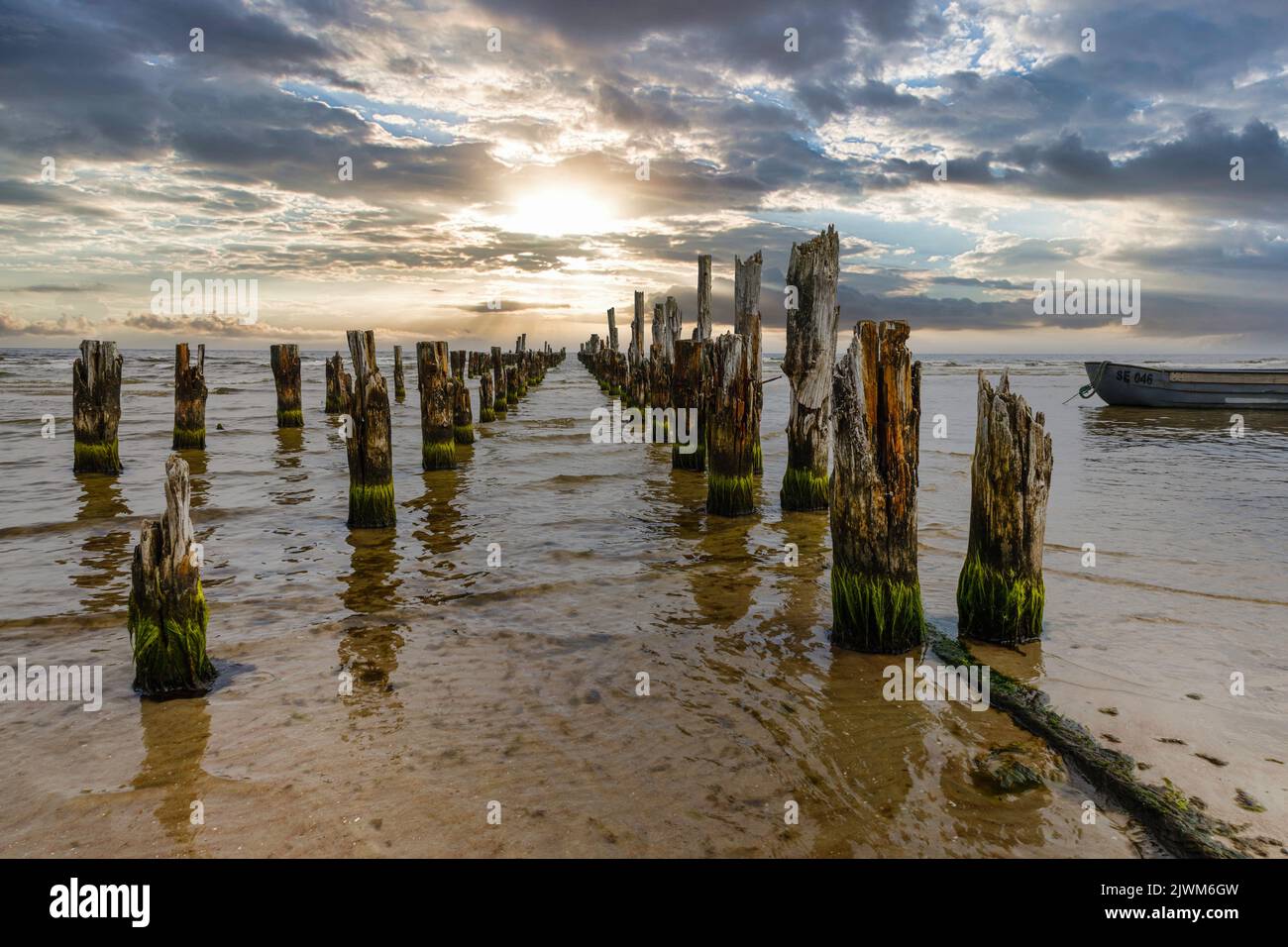 Old abandoned wooden pier or jetty remains and fishermen's boat Stock Photo