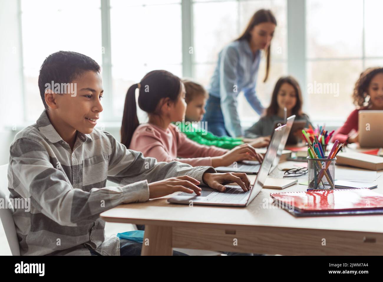 Cheerful Black Schoolboy Using Laptop Computer Learning Online In Classroom Stock Photo