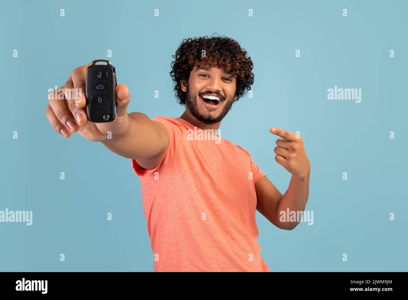 Cheerful driver young bearded Indian man holding new car key Stock Photo