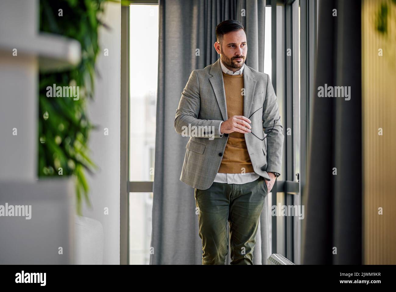 Elegant entrepreneur businessman, taking a stroll through his office, carrying his glasses, stylish. Stock Photo