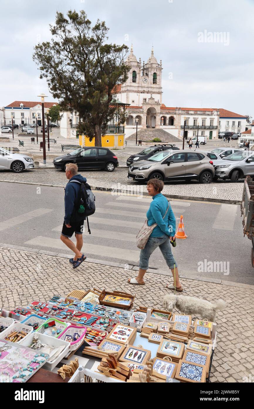 NAZARE, PORTUGAL - MAY 22, 2018: Tourists walk by local artisanal craft products and souvenirs in market stalls in Nazare, Portugal. Stock Photo