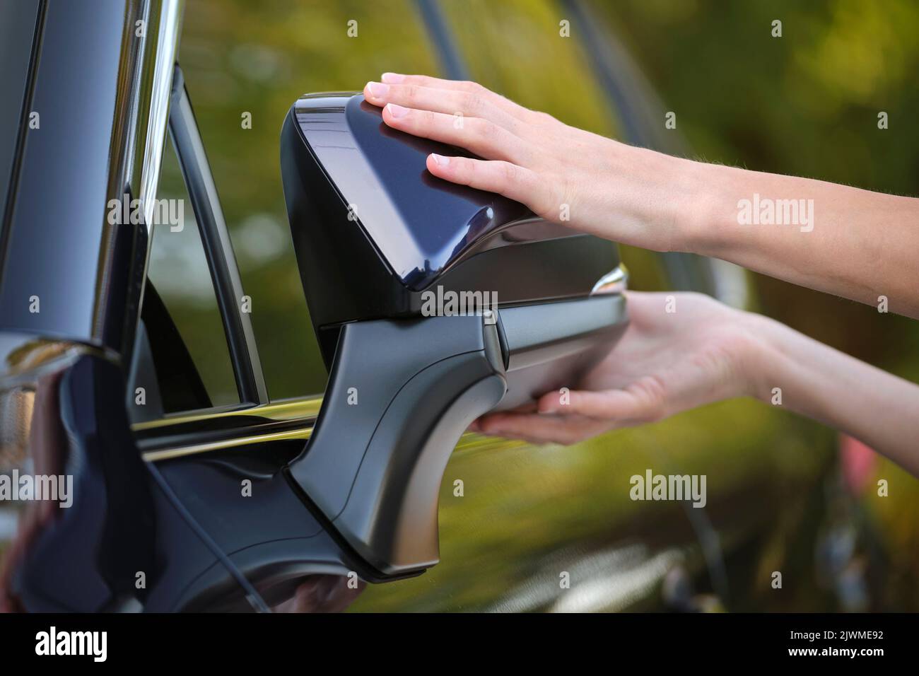 Driver hands adjusting side view mirror of a car Stock Photo