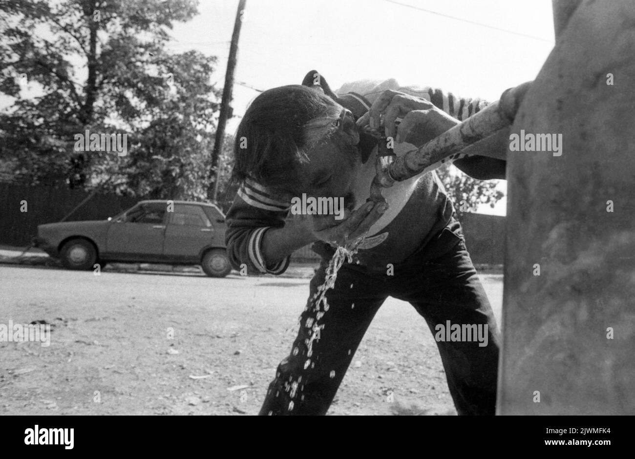 Bucharest, Romania, 1990. Man drinking from a water fountain on the street. Stock Photo