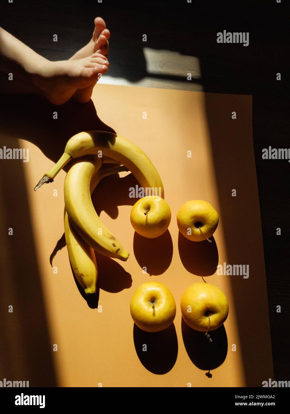 Legs of a small child - on the background of bananas and apples Stock Photo