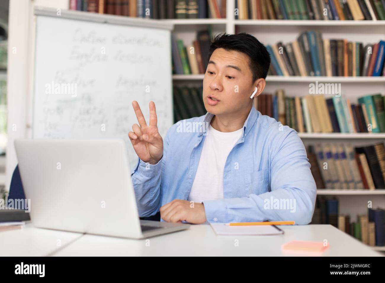 Asian Male Teacher Making Video Call Using Laptop In Library Stock ...