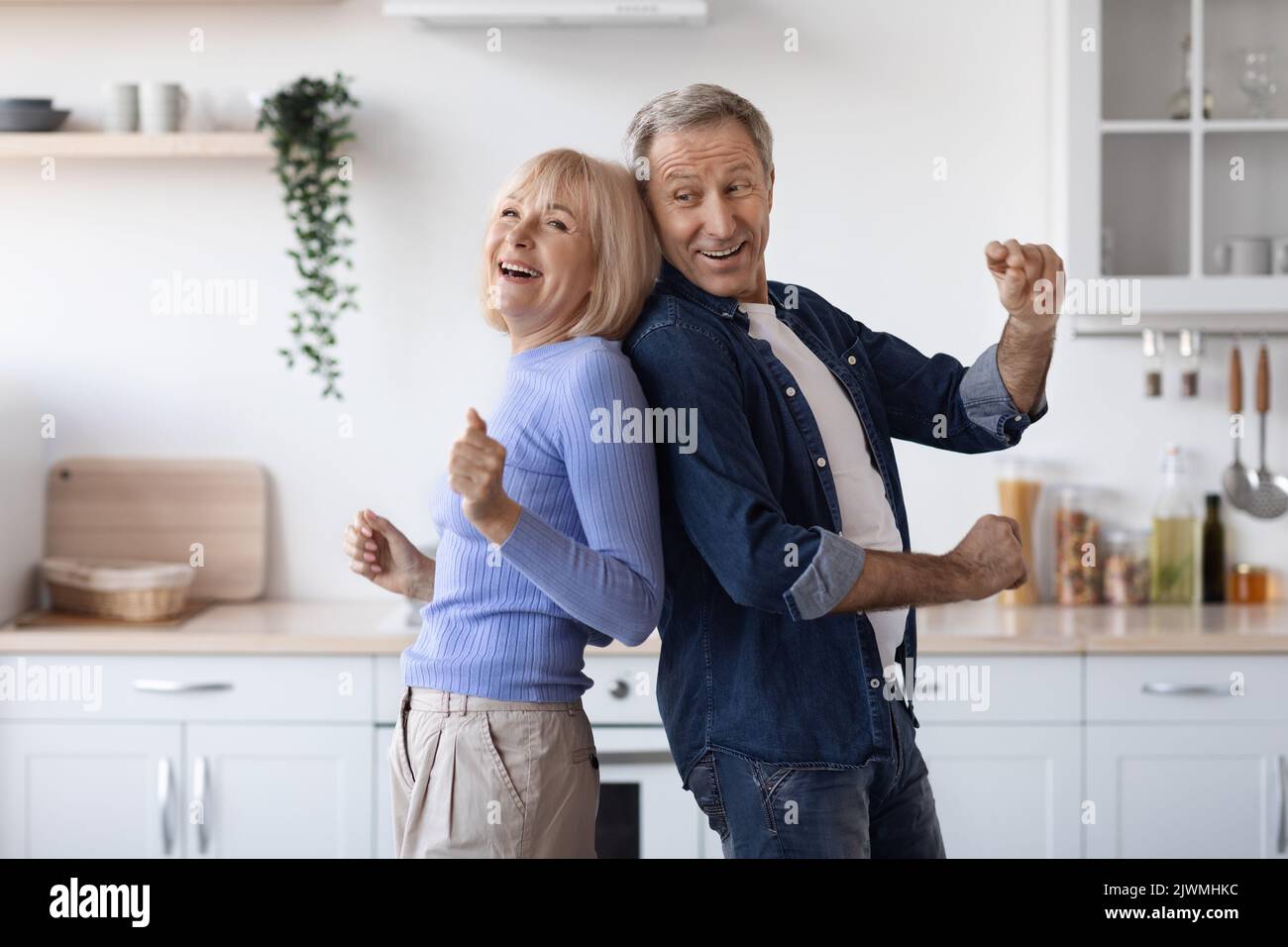 Joyful elderly spouses dancing together at kitchen Stock Photo