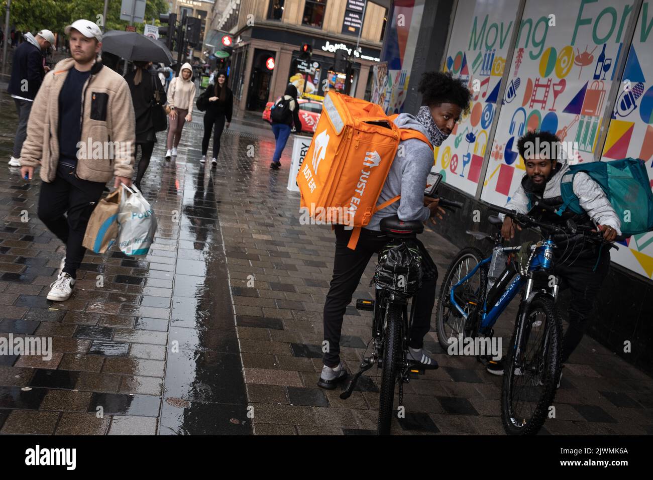 Fast food delivery couriers, for Deliveroo, and Just Eat, in Glasgow, Scotland, 6 September 2022. Stock Photo