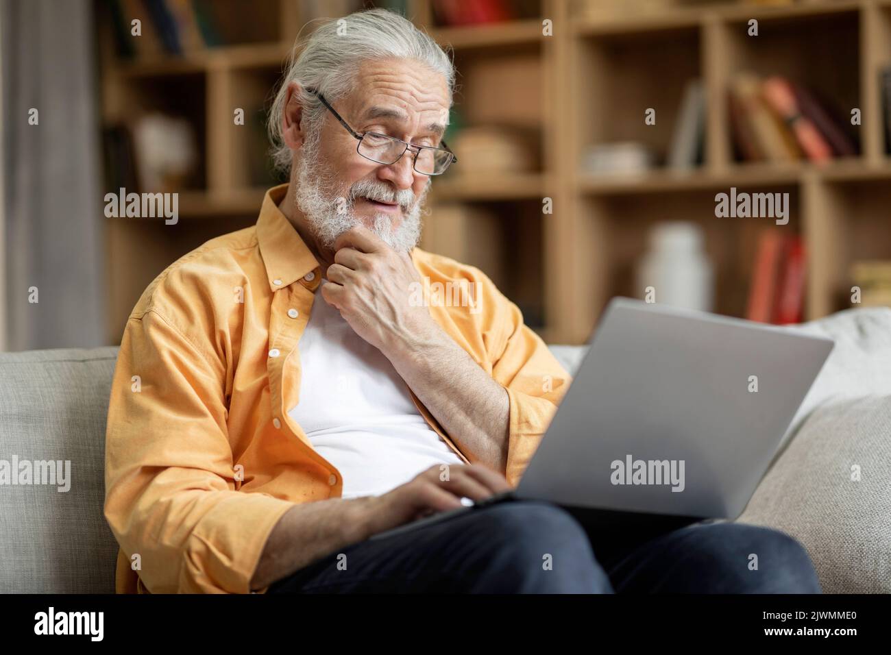 Cheerful senior man using laptop at home Stock Photo