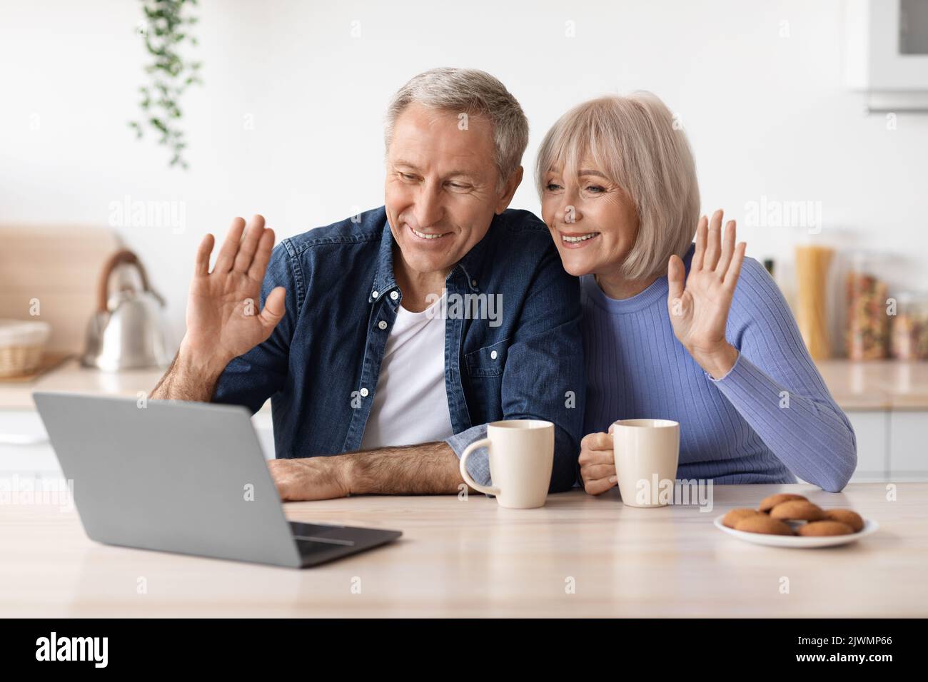 Cheerful elderly couple making video call while drinking coffee Stock Photo