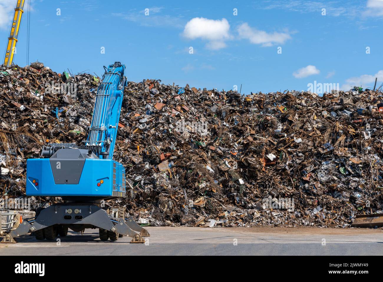 A large pile of scrap metal and waste at a recycling plant with a blue ...