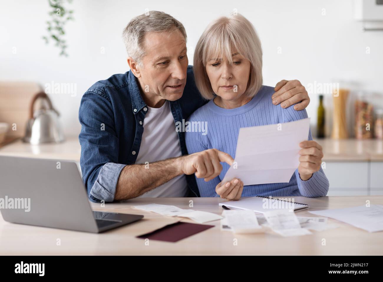 Serious pensioners sittting in front of computer, reading letter Stock Photo