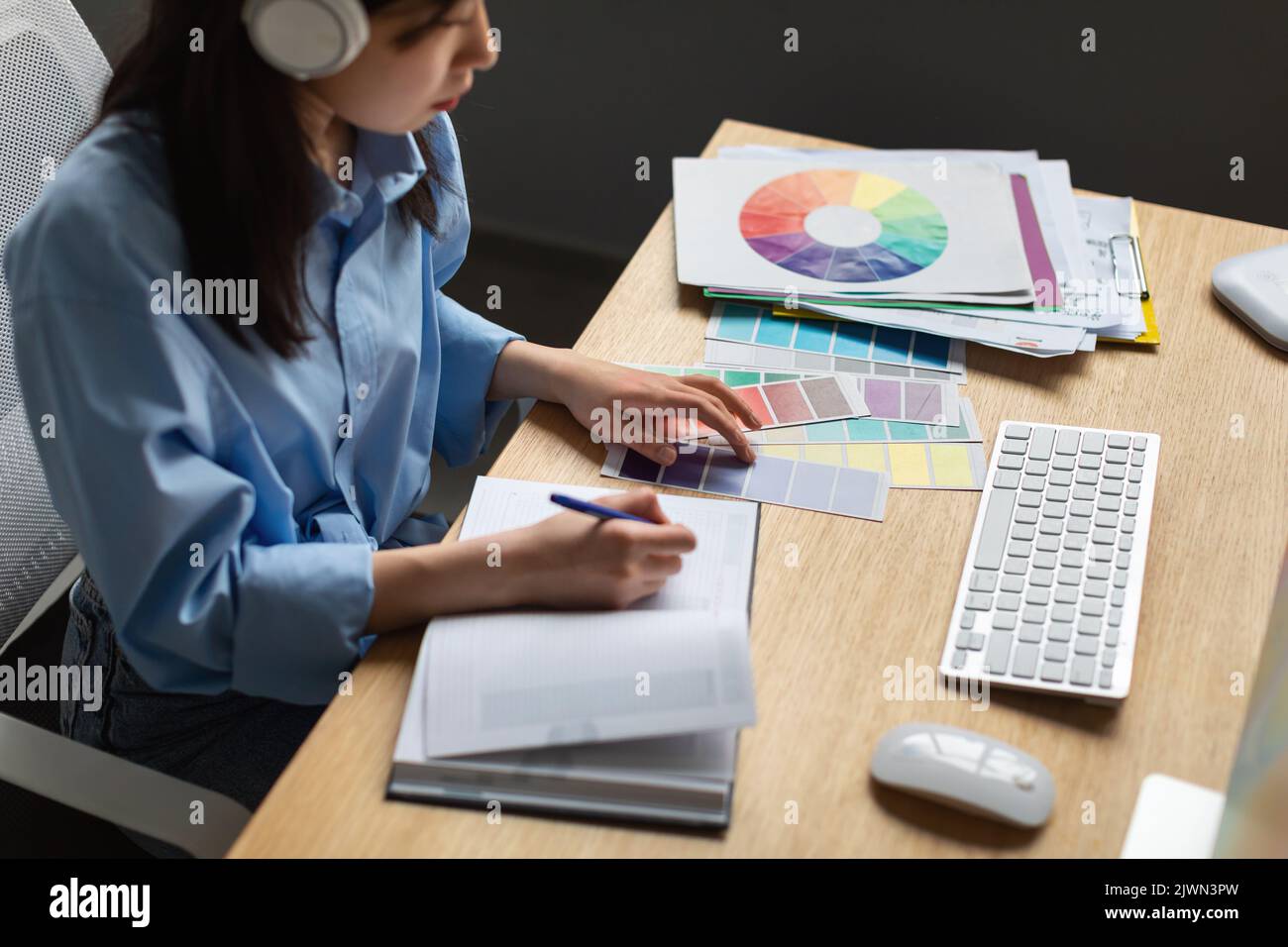 asian-woman-with-headphones-writing-learning-graphic-design-online