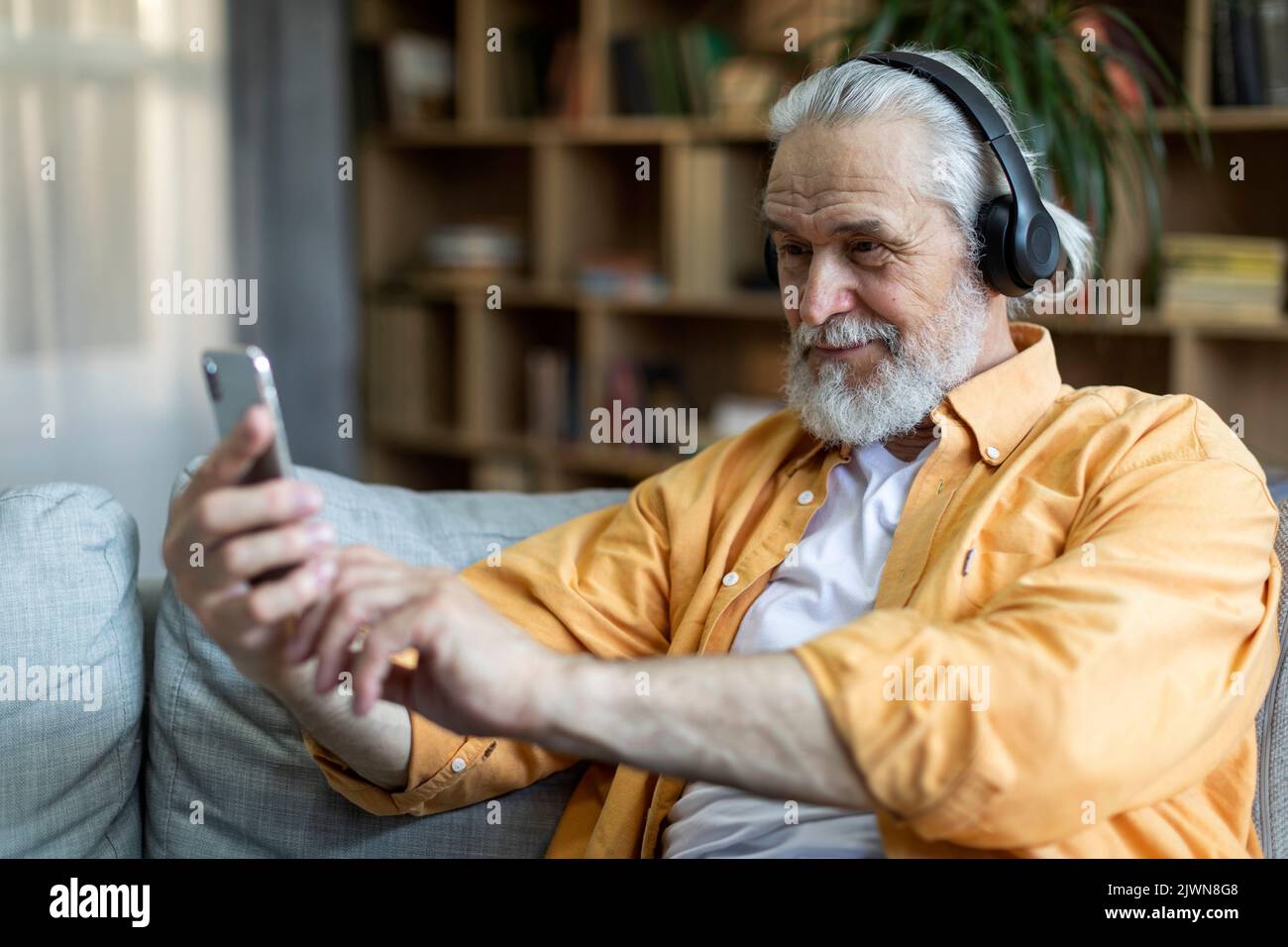 Positive grandfather using wireless headset and cell phone Stock Photo